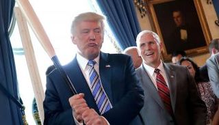 ترامب ممسكا بمضرب أمام نائبه مايك بنس في البيت الأبيض (رويترز)