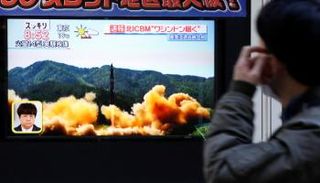 أحد المارة يشاهد تجربة صاروخ بالستي كوري شمالي في شارع بطوكيو (رويترز)