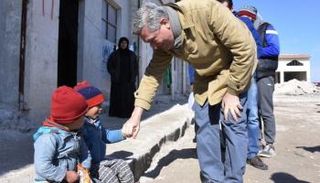 مسئول بمفوضية اللاجئين يداعب أطفال بحلب