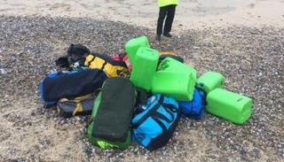 شرطي بجوار حقائب تحتوي على كوكايين قذفتها مياه البحر على شاطئ هوبتون