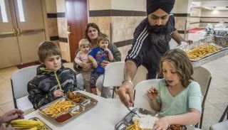 أحد المتطوعين في المعبد يعطي الطعام لأفراد عائلة ليون - صحيفة الجارديان