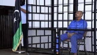 سيف الإسلام القذافي لدى حضوره جلسة استماع خلف القضبان في محكمة بالزنتان