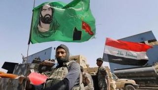 راية طائفية يرفعها أحد جنود الحشد الشعبي (رويترز)