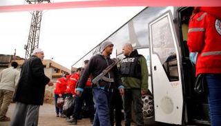 أشخاص يغادرون حي الوعر بأسلحتهم (أرشيف رويترز)