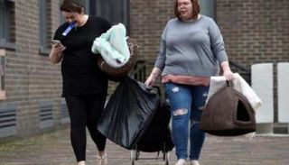 أشخاص يحملون ممتلكاتهم وهم يغادرون أحد الأبراج