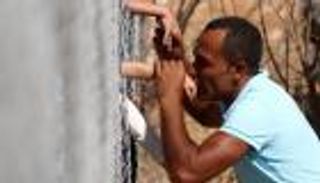 لقطات تحطم القلوب.. سوري يقبل أطفاله خلف سياج