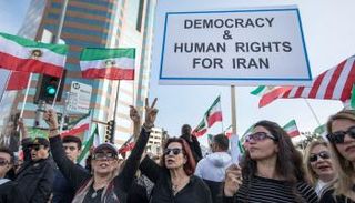 إيرانيات يحملن لافتة كتب عليها الديمقراطية والحرية لإيران - رويترز