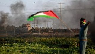 شاب فلسطيني يرفع العلم قرب حدود غزة