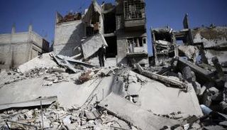 رجل يقف وسط الدمار جراء قصف قوات النظام للغوطة - رويترز