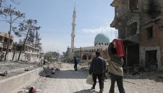 سوريون يحملون أمتعتهم في طريق الخروج من الغوطة