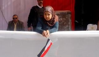 طفلة تحمل علم مصر أمام إحدى لجان التصويت