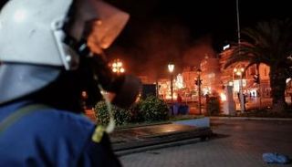 رجل شرطة يوناني يراقب أحد المواقع التي شهدت اشتباكات