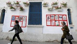 فتاتان تمران بجانب ملصقات الانتخابات البلدية - رويترز