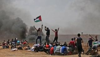 شباب فلسطيني يرفع العلم أثناء احتجاجات ذكري النكبة