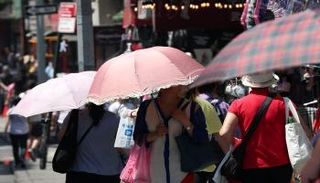 أناس يحتمون من حرارة الشمس في الحي الصيني بمانهاتن بنيويورك  