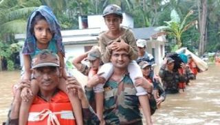 أحد المتضررين من فيضان كيرلا يحمل طفله وسط المياه