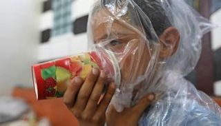 طفل سوري يجرب الكمامة البدائية للوقاية من هجوم كيميائي