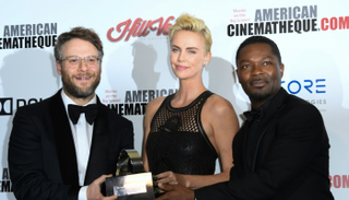 تشارليز ثيرون تحمل جائزتها وتتوسط سيث روجن وديفيد أويلوو