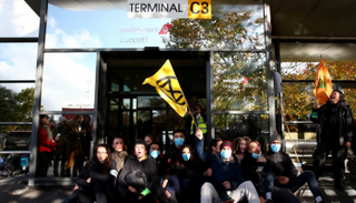 النشطاء يجلسون أمام مبنى مدرج الطائرات الخاصة بمطار جنيف