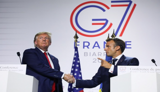 دونالد ترامب يصافح إيمانويل ماكرون - رويترز