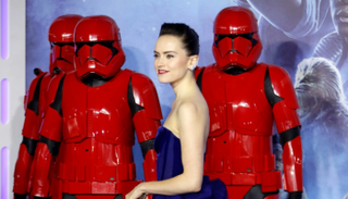 الممثلة دايزي ريدلي محاطة بروبوتات من فيلم "ستار وورز" 