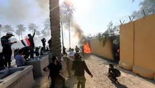 عناصر مليشيا حزب الله العراقية يضرمون النيران بسور السفارة الأمريكية ببغداد