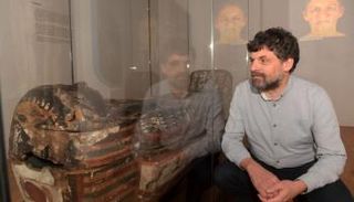 نيل كورتيس بجوار المومياء وفي الخلف الصورة التي توصلت لها الأشعة