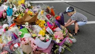 طفل يضع باقة خارج مسجد النور عند نصب تذكاري لضحايا الاعتداء