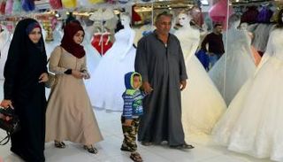عراقيون يمرون أمام متجر لبيع فساتين أعراس 