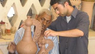 أحد عمال الفخار يراجع المنتج بعد تشكيل الطين