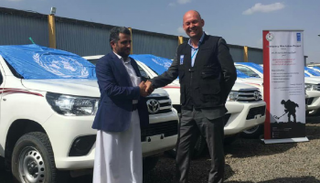 مسؤول أممي يصافح قياديا حوثيا أثناء تسليم السيارات بصنعاء