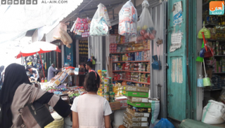 فلسطينية برفقة ابنتها تشتري الحلوى في أحد محال غزة