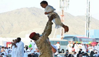 أحد رجال الأمن يرسم البهجة على وجه طفل خلال موسم الحج