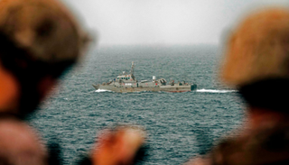 جنديان أمريكيان يراقبان زورقا إيرانيا في مضيق هرمز