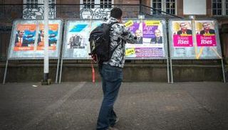 فرنسي أمام لافتات دعائية لانتخابات البلدية 