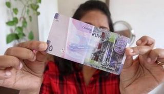 فتاة تحمل عملة الدينار الكويتي