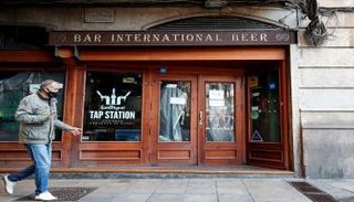 رجل يمر أمام مطعم مغلق في برشلونة