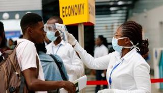 مسؤولة بأحد المطارات تقيس درجة حرارة مسافر