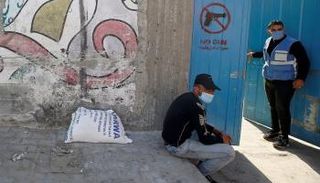 فلسطينيان يرتديان الكمامة في مقر تابع للأونروا في غزة