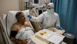 ممرضة تتولى إطعام مريض بفيروس كورونا