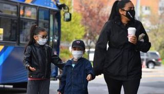 سيدة وطفلاها يضعون الكمامات للحماية من كورونا