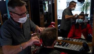 حلاق فرنسي يقص شعر أحد الزبائن