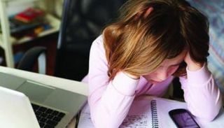 فتاة تجلس أمام جهاز كمبيوتر - تعبيرية