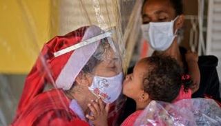 ماما نويل تقبل طفلة من وراء ستار بلاستيكي