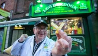 ديريك دوجان يحمل أصبعي بطاطا مقليين أمام مطعمه 