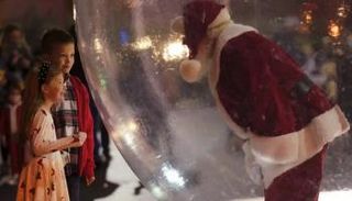 طفلان يتحدثان مع بابا نويل المحتمي بفقاعة