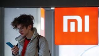 رجل يستخدم هاتفه الذكي بجوار العلامة التجارية Xiaomi بوسط كييف