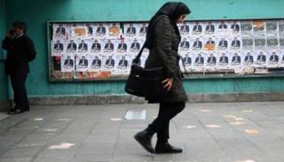 امرأة تمشي أمام دعاية انتخابية إيرانية - رويترز