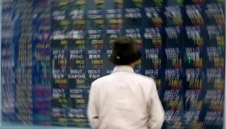 أحد المشاة ينظر إلى لوحة عروض لأسعار الأسهم للشركات اليابانية 
