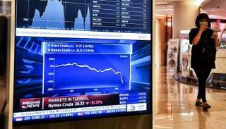 امرأة ترتدي قناعًا تتخطى لوحة إلكترونية تعرض مؤشر الأسهم الآسيوي 